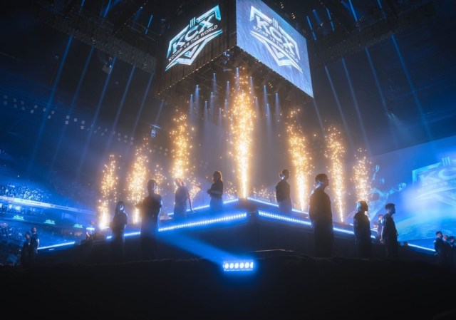 K-Corp vs The World 2023, che mostra più giocatori sul palco con luci blu che evidenziano l'arena