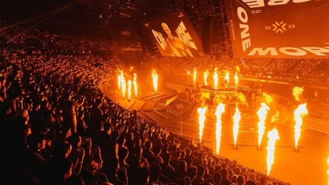 Una folla enorme guarda i grandi schermi su cui è scritto "ONE MORE".  Le loro sagome sono illuminate da molteplici colonne di fuoco.